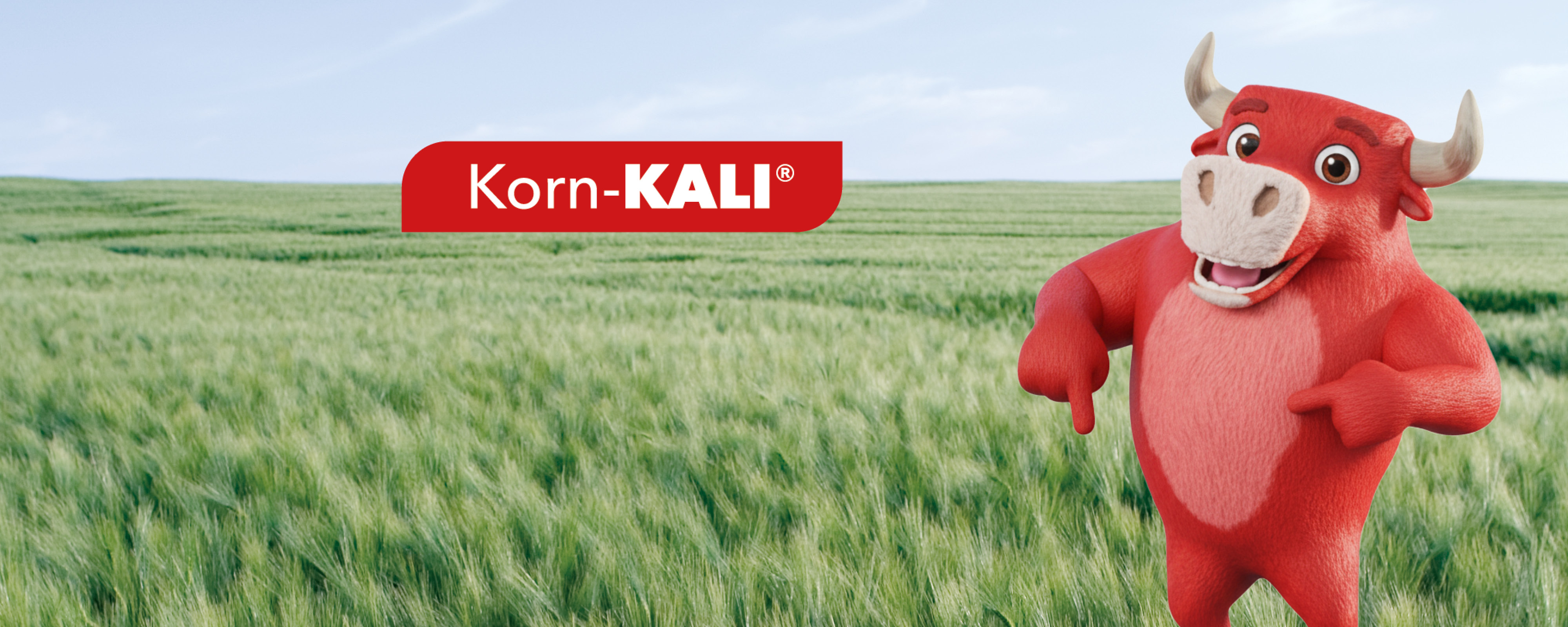 Rotes Korn-KALI-Maskottchen steht auf grünem Feld vor Himmel mit Schriftzug „Vor uns gesichert. Für euch #bereit.“