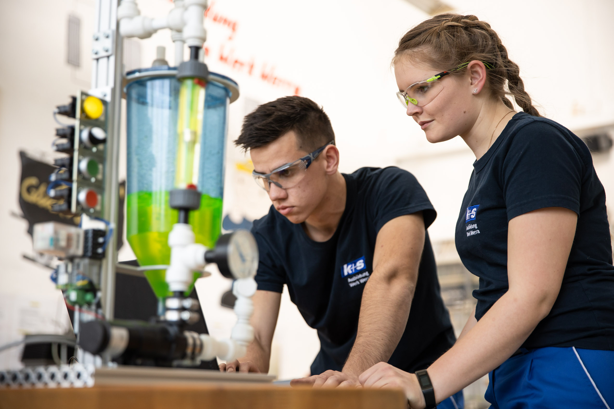 Zwei Chemikant:innen betrachten gemeinsam ein Reagenzglas im Labor