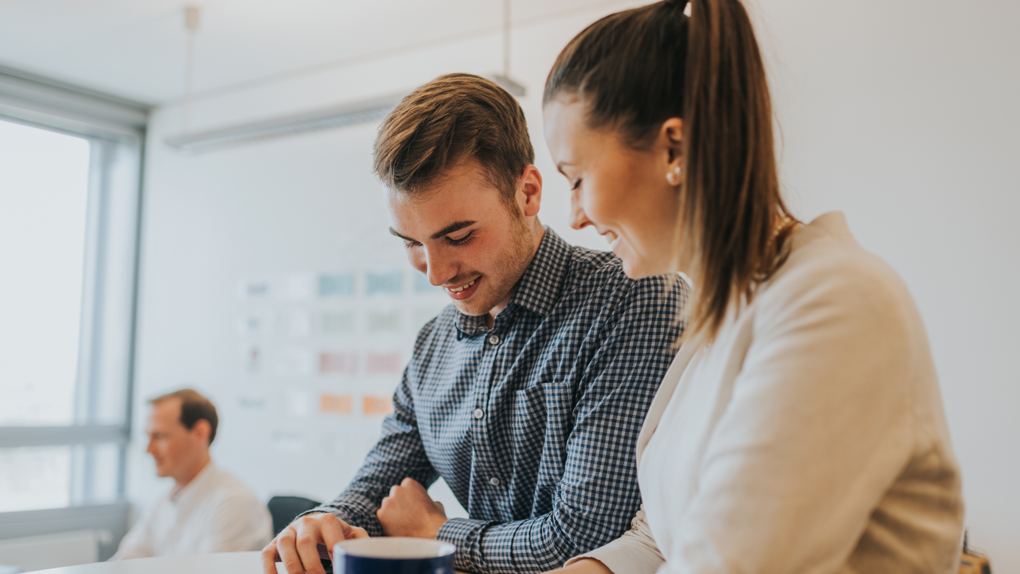 Zwei duale Betriebswirtschafts-Studierende schauen auf ein Tablet.