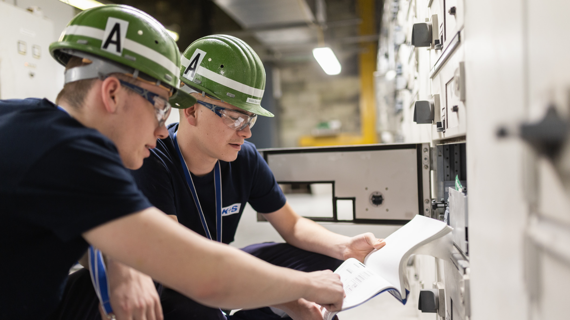 Duale Elektrotechnik-Studierende an Schaltanlagen.
