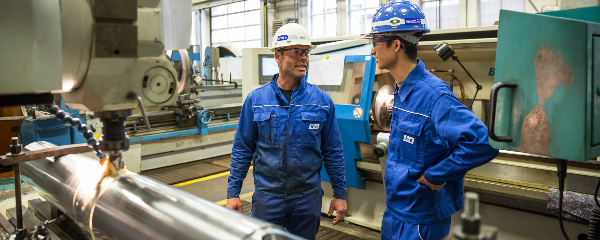Ausbilder und Azubi im Gespräch an der Drehmaschine