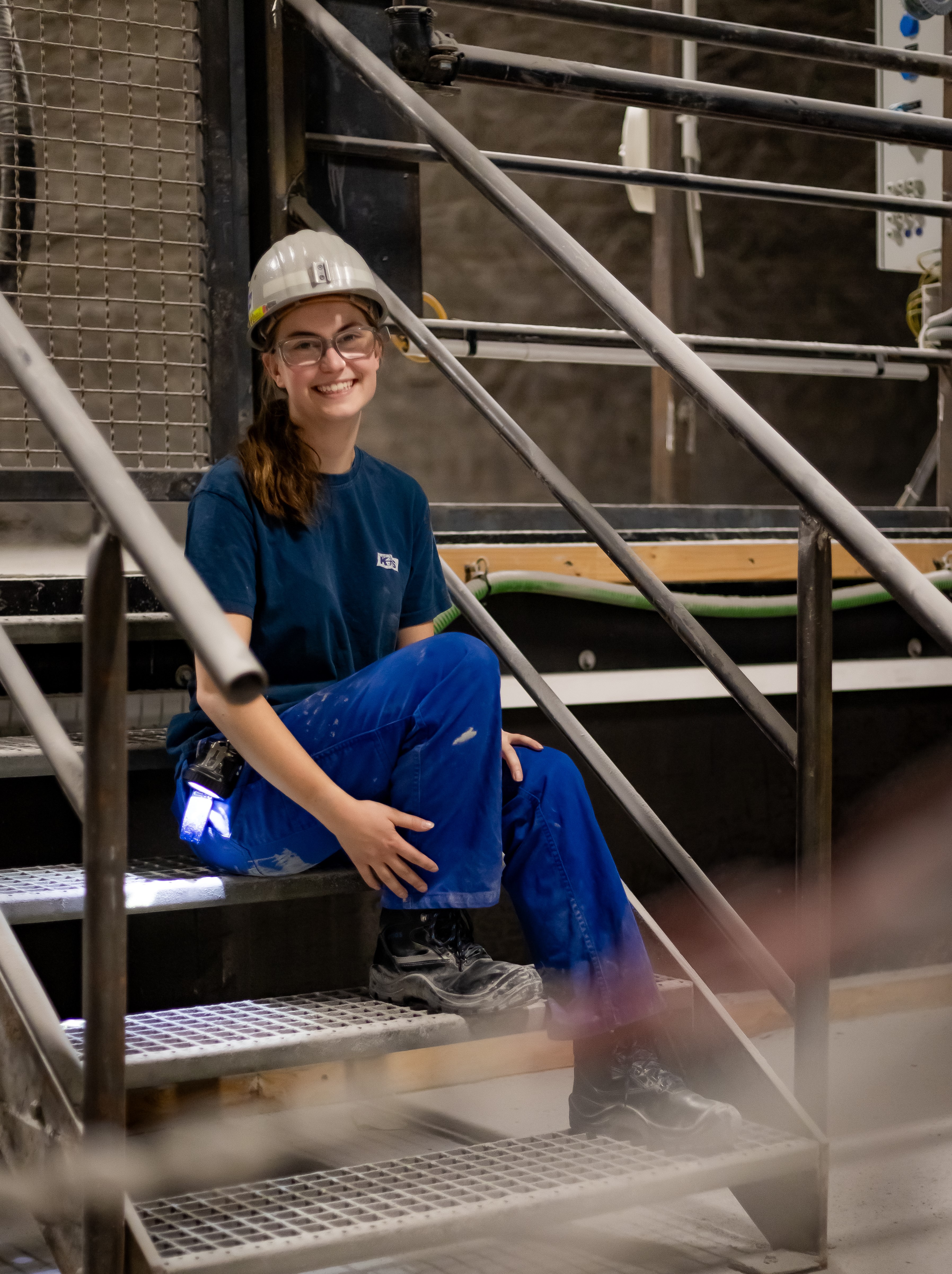 Werkstudentin sitzt unter Tage und lächelt in die Kamera.