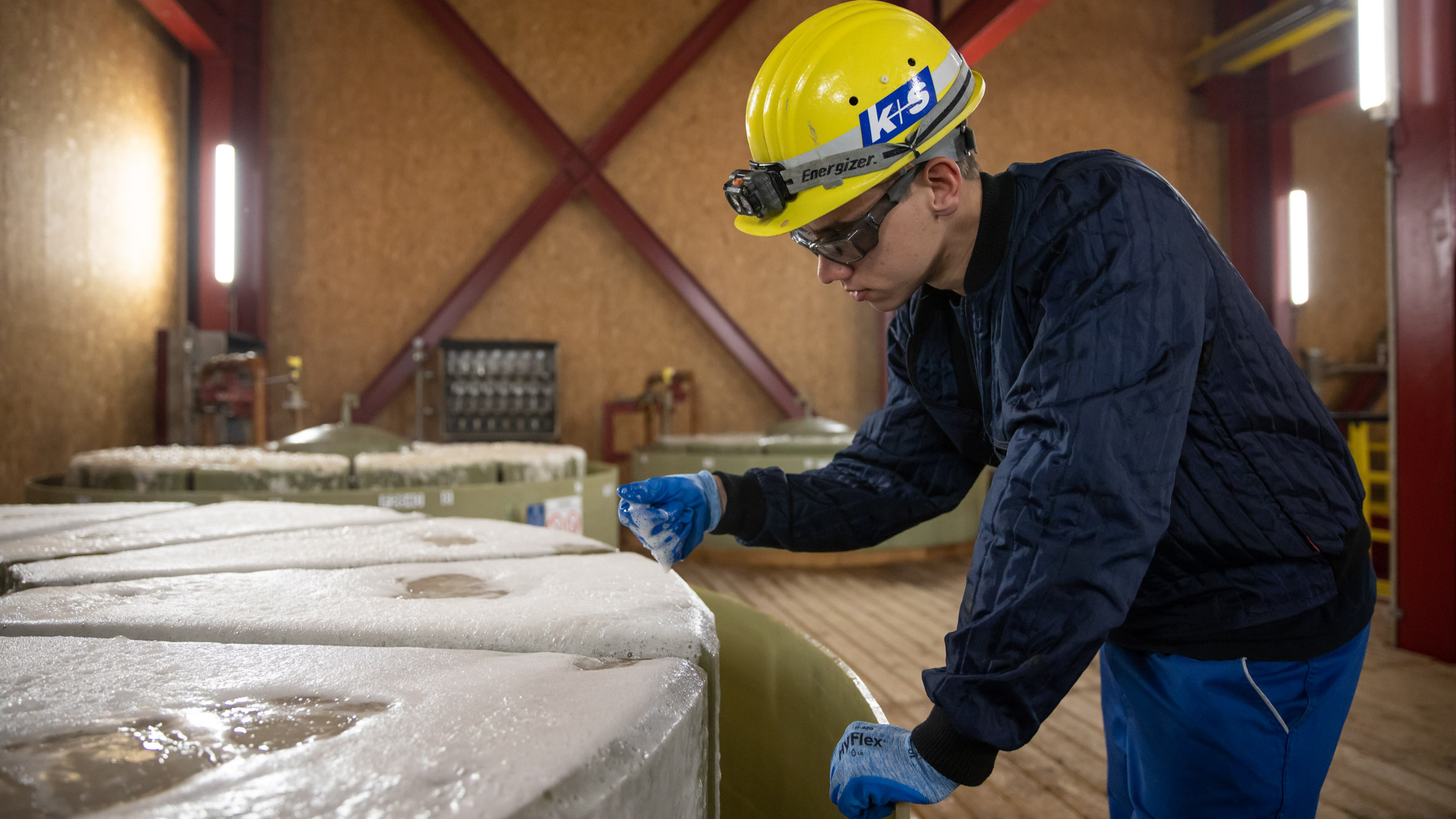Azubi in der Produktion, hat Schaum in der Hand. 