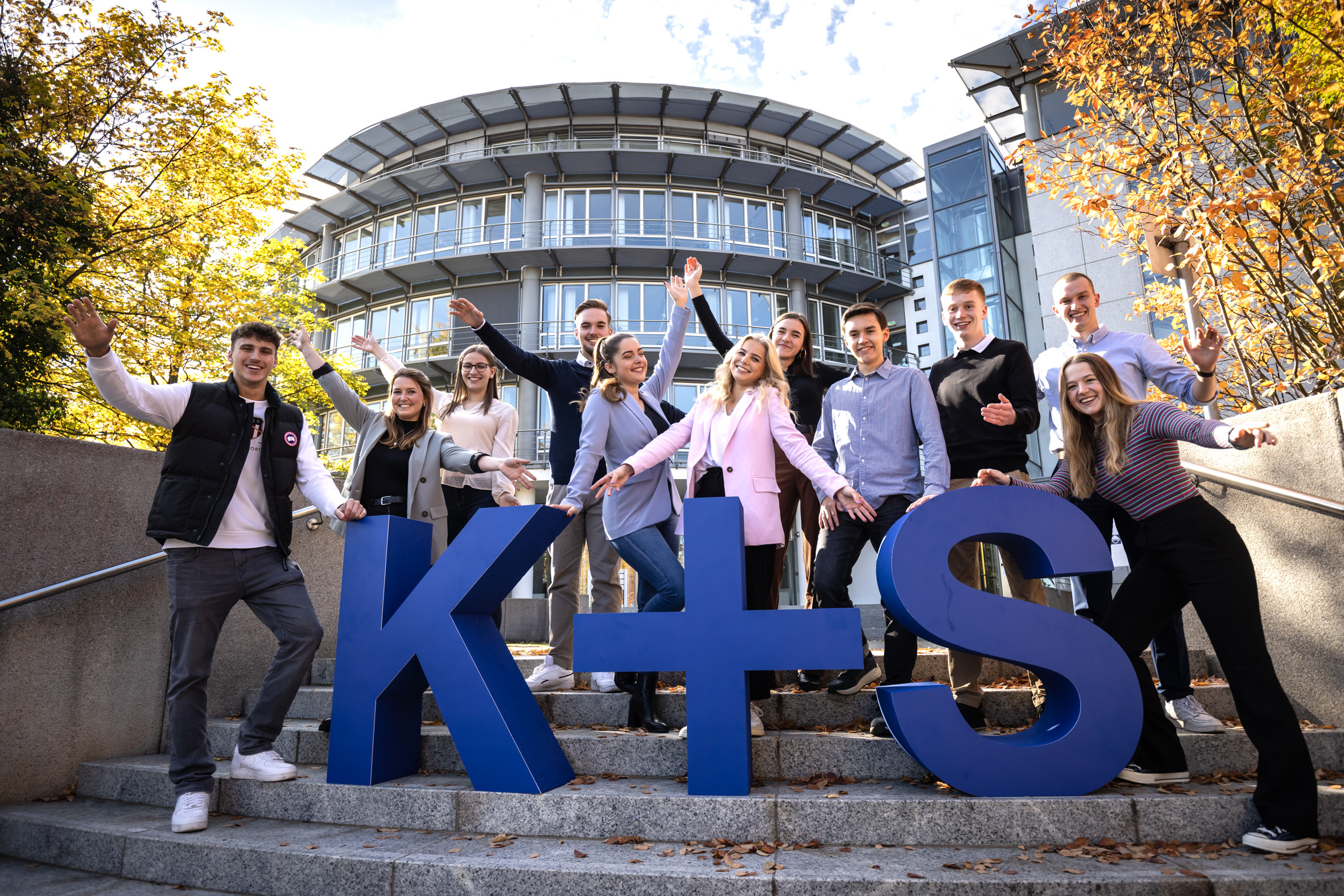 K+S trainees stand in front of the company building with large K+S lettering.