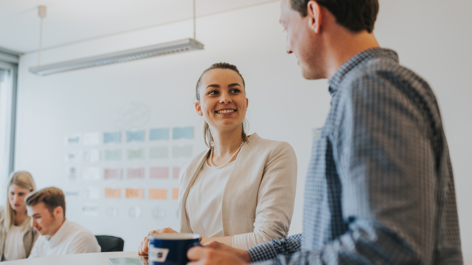 Duale Studierende im Gespräch bei einer Kaffeepause im Büro.