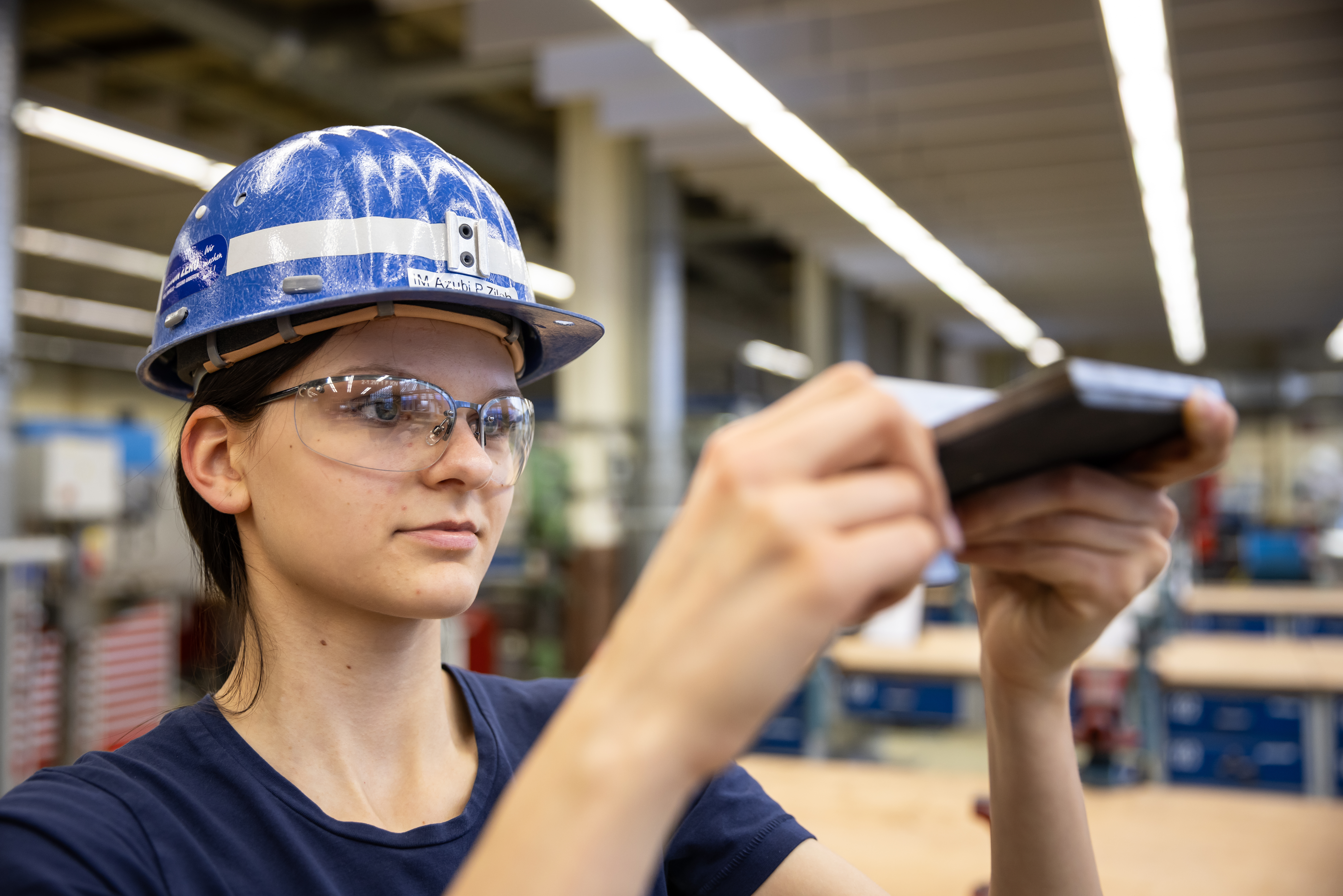 Auszubildende Industriemechanikerin prüft ein Werkstück