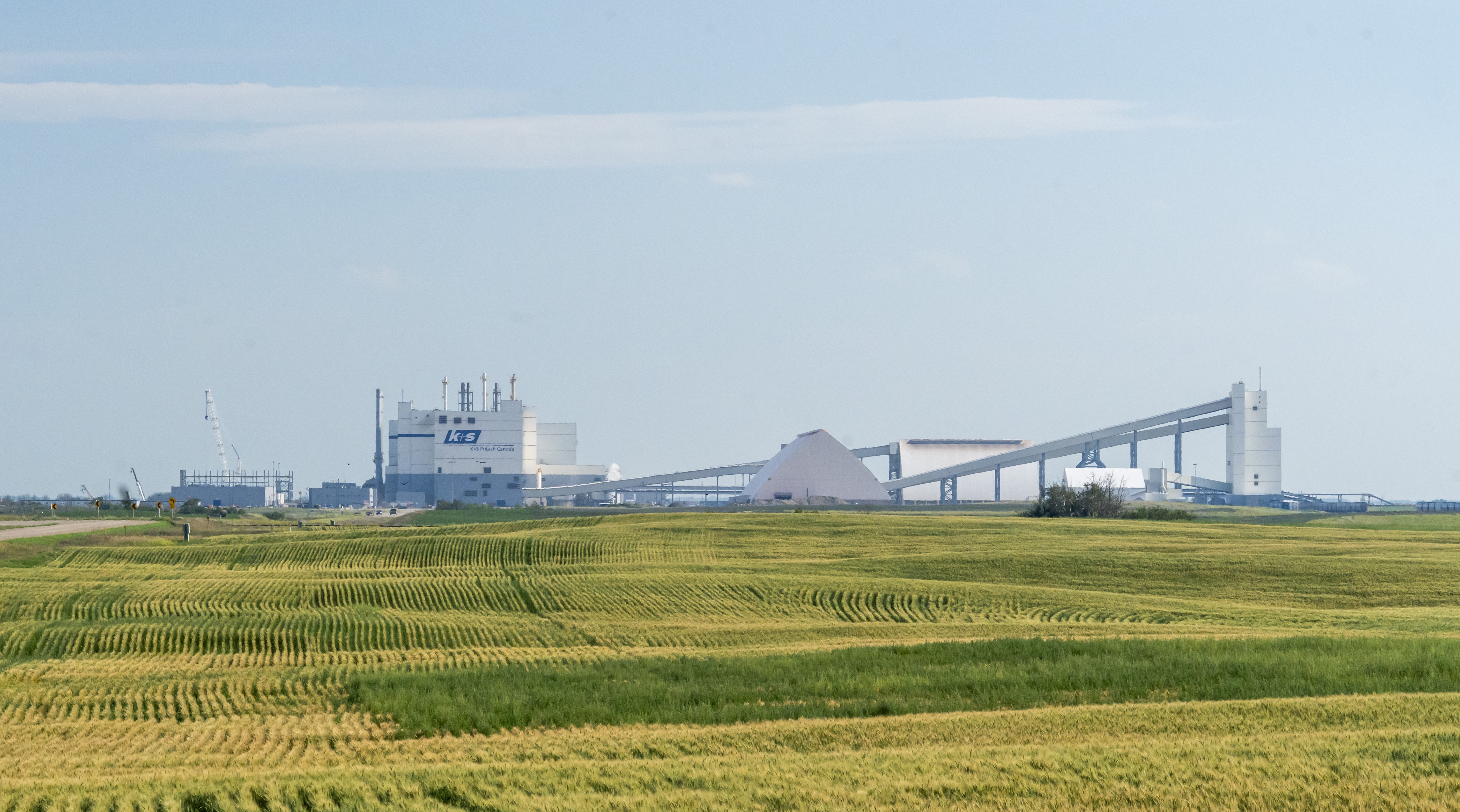 Green grass stretches out in the foreground. The K+S Potash Canada building can be seen on the horizon.