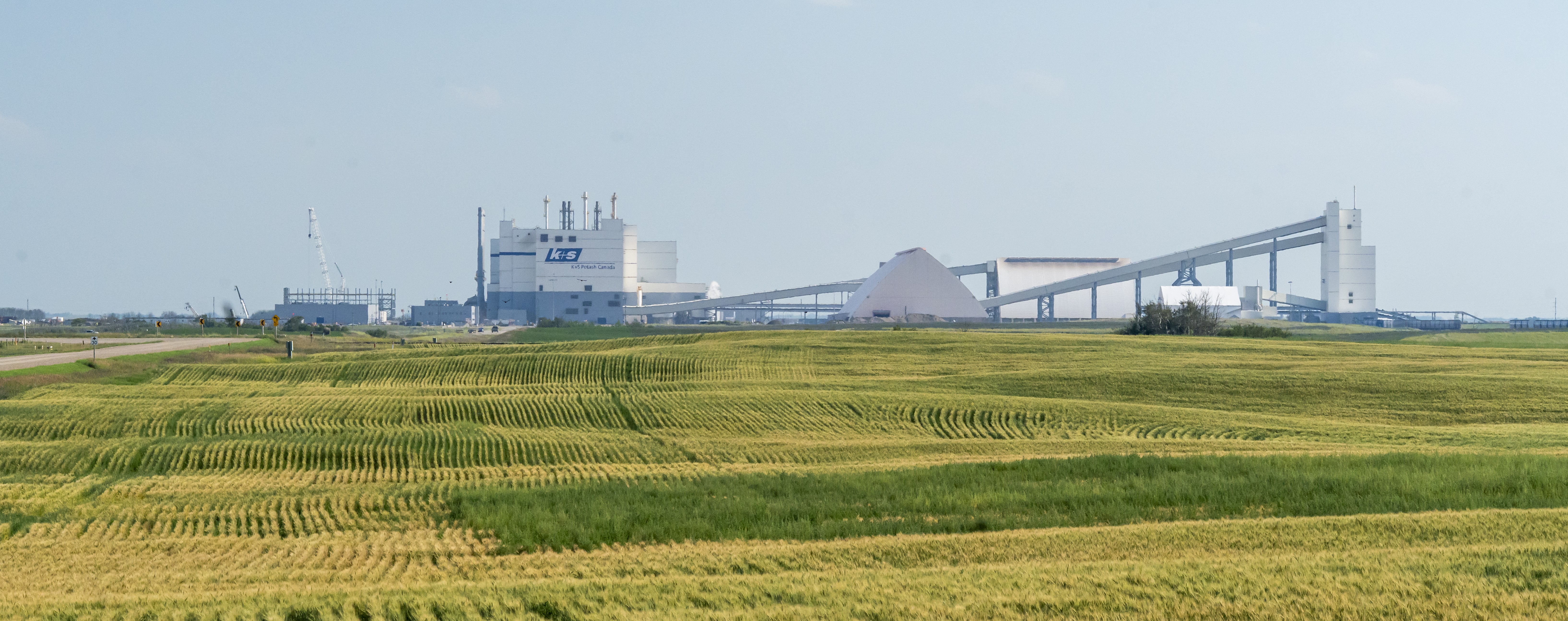 Green grass stretches out in the foreground. The K+S Potash Canada building can be seen on the horizon.