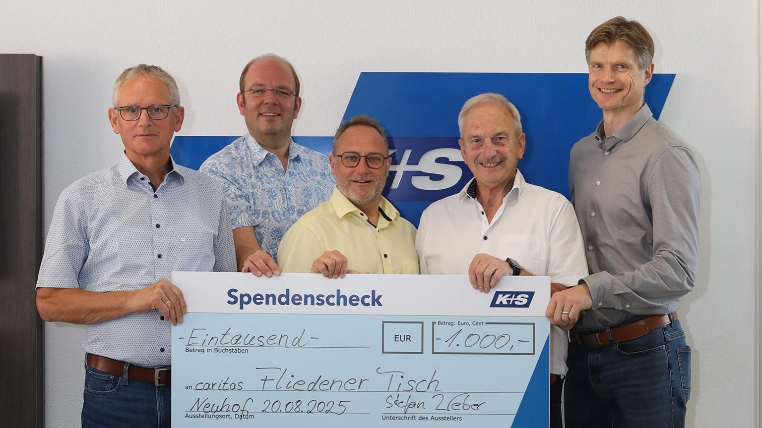 Fünf lächelnde Männer halten gemeinsam einen großen Spendenscheck über 1.000€ für den Fliedener Tisch in den Händen