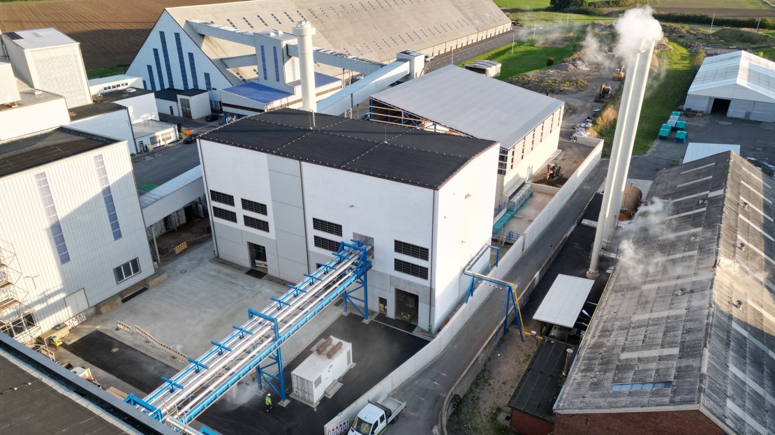 Luftaufnahme in Borth auf dem Industriekomplex von K+S mit einem großen weißen Gebäudeblock und einem angeschlossenen blauen Rohrleitungssystem. Im Hintergrund sind weitere Hallen, technische Anlagen und Grünflächen.