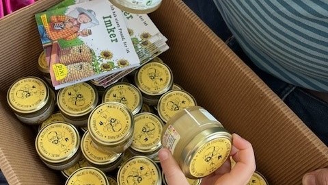 A box full of small honey glasses and books about beekeeping.