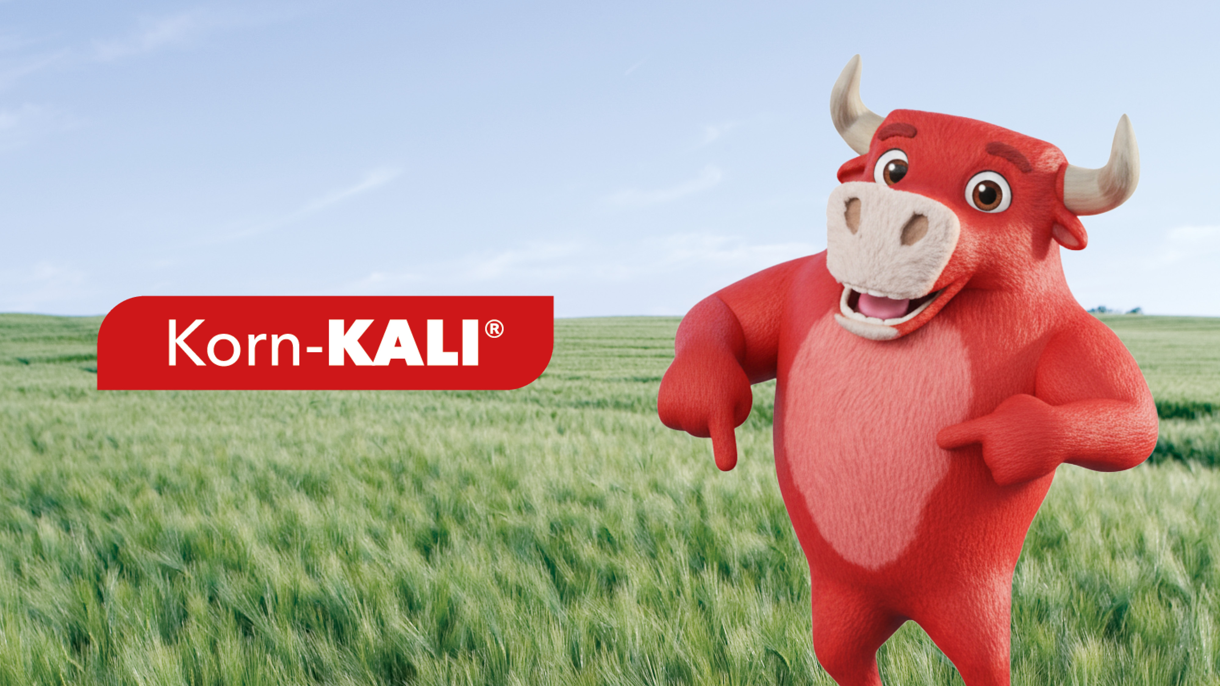 Rotes Korn-KALI-Maskottchen steht auf grünem Feld vor Himmel mit Schriftzug „Vor uns gesichert. Für euch #bereit.“
