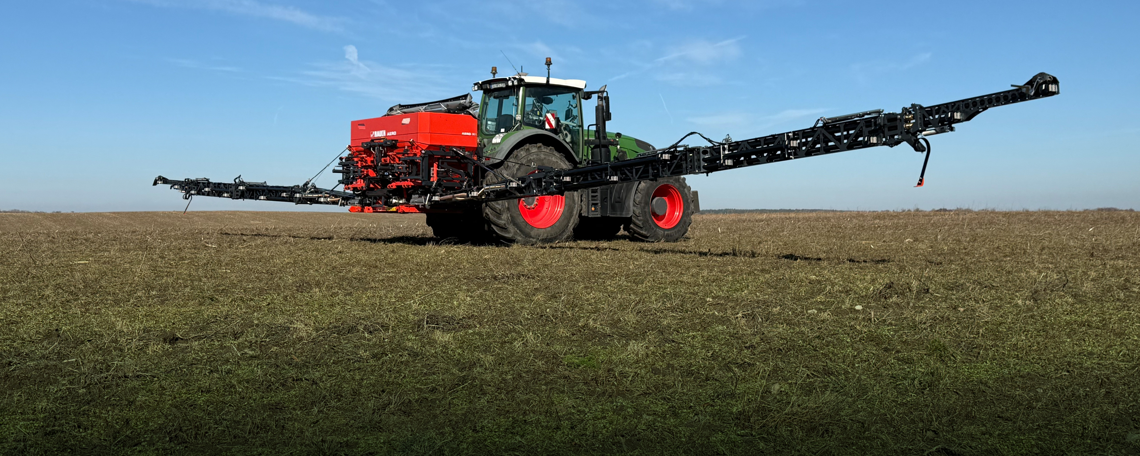 Tractor with attached fertilizer spreader applying mineral fertilizer.