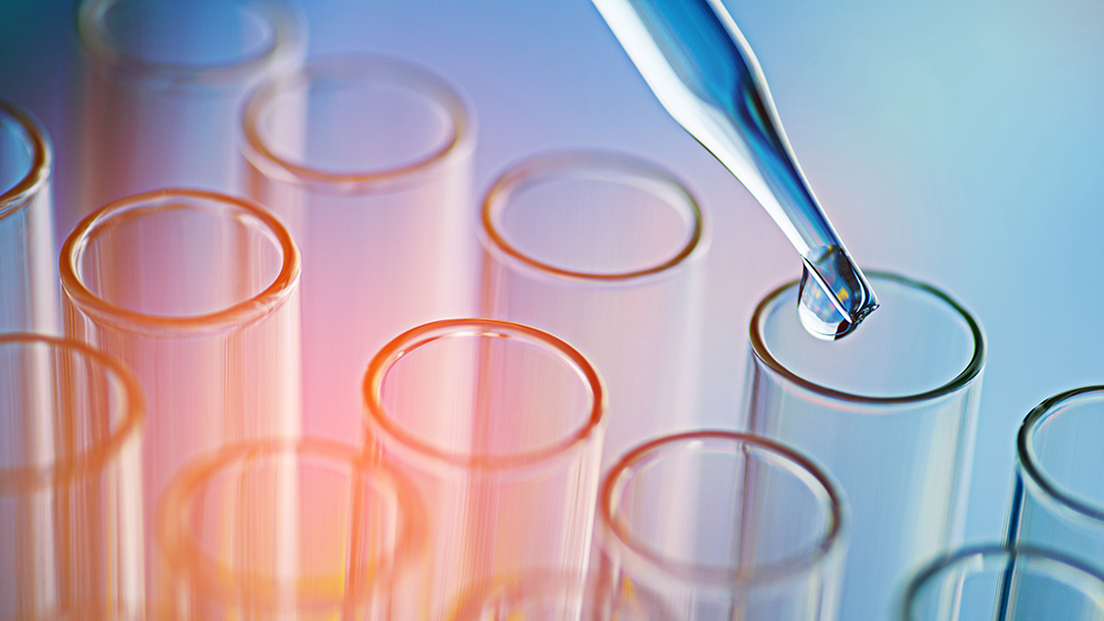 Several transparent test tubes with colored light reflections while a pipette drips liquid into one tube.