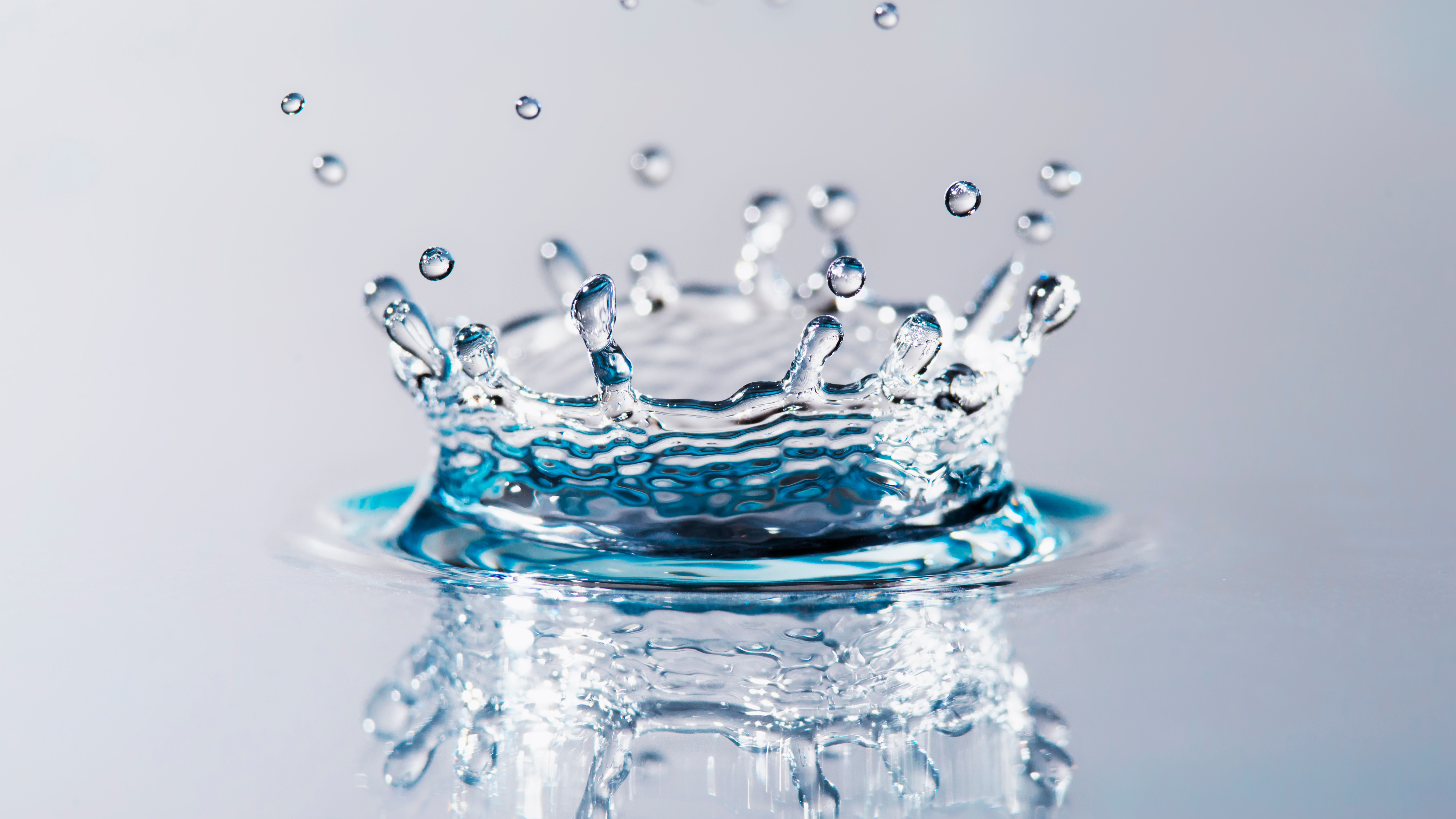Close-up of a water droplet hitting a water surface, forming a crown-shaped splash.